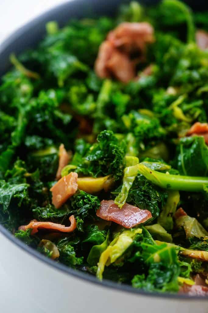 skillet full of green vegetables and prosciutto.