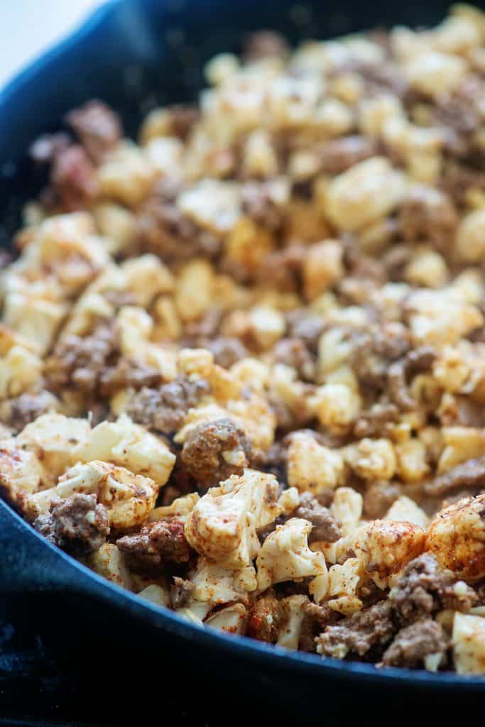 seasoned beef and cauliflower in cast iron skillet.