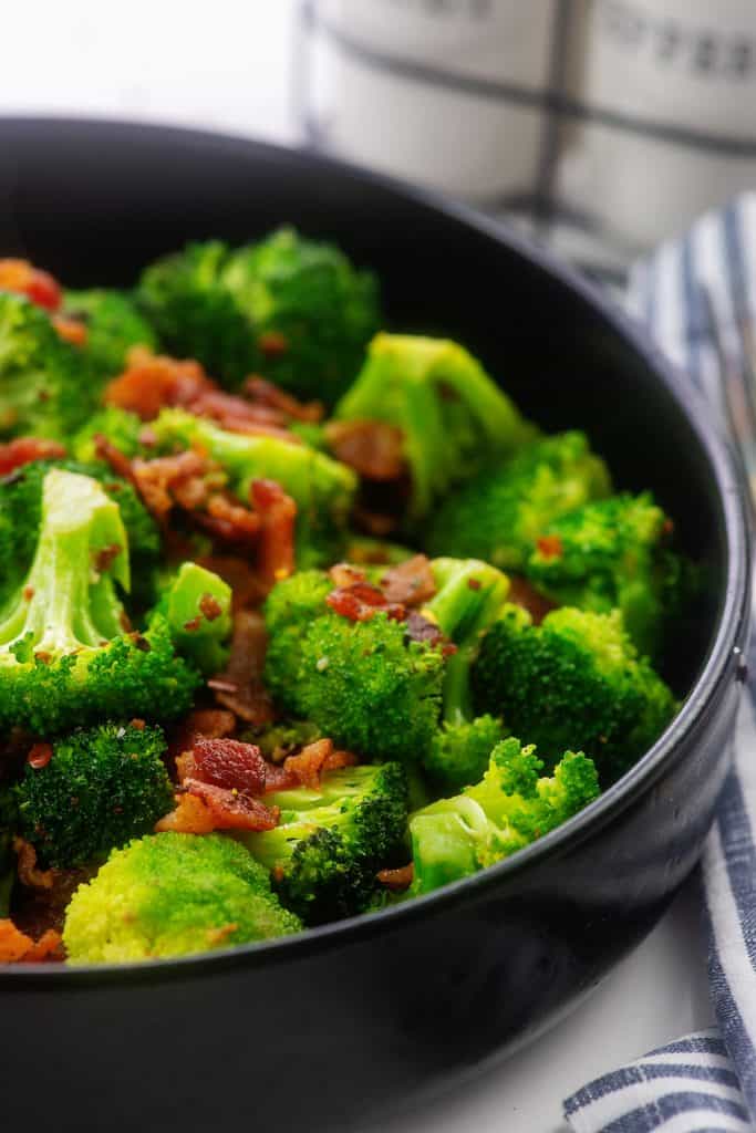 bowl full of cooked broccoli with bacon and garlic.