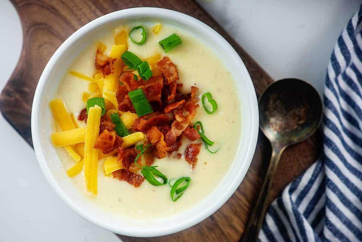 bowl full of cauliflower soup on wooden board.