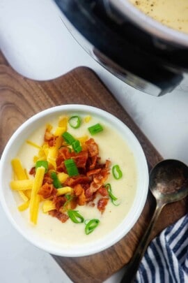 cheesy cauliflower soup recipe in white bowl.