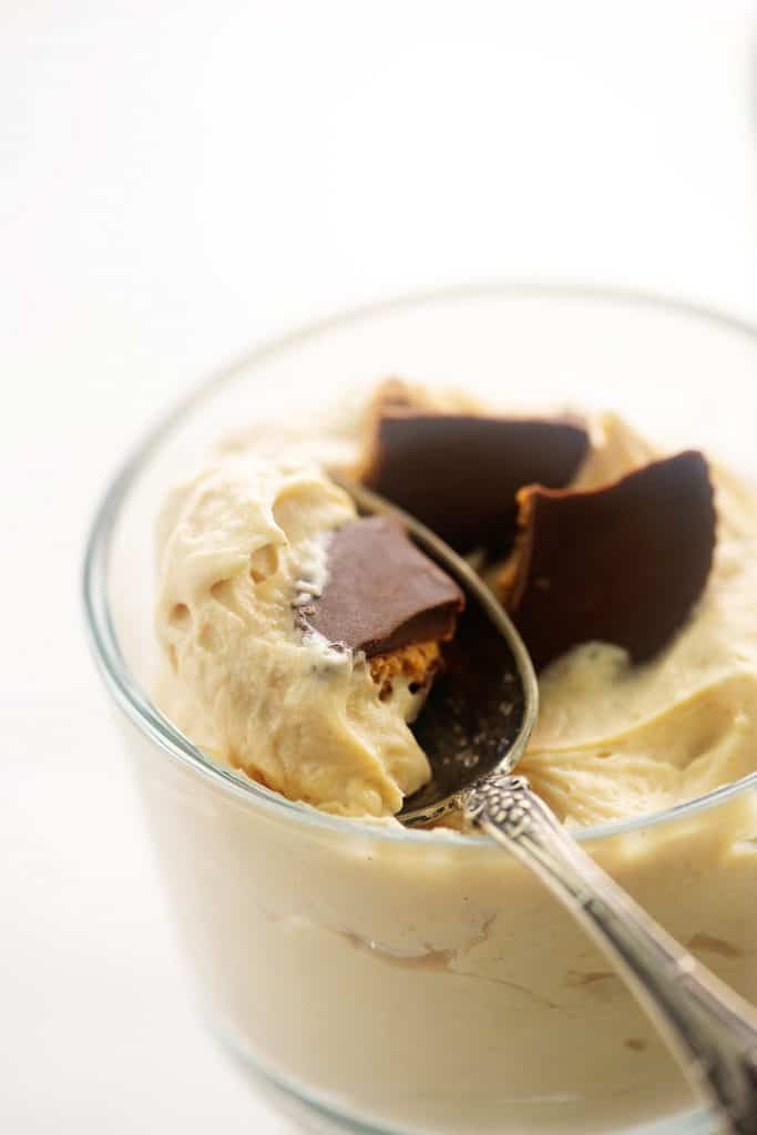 creamy peanut butter mousse in glass dish with spoon.