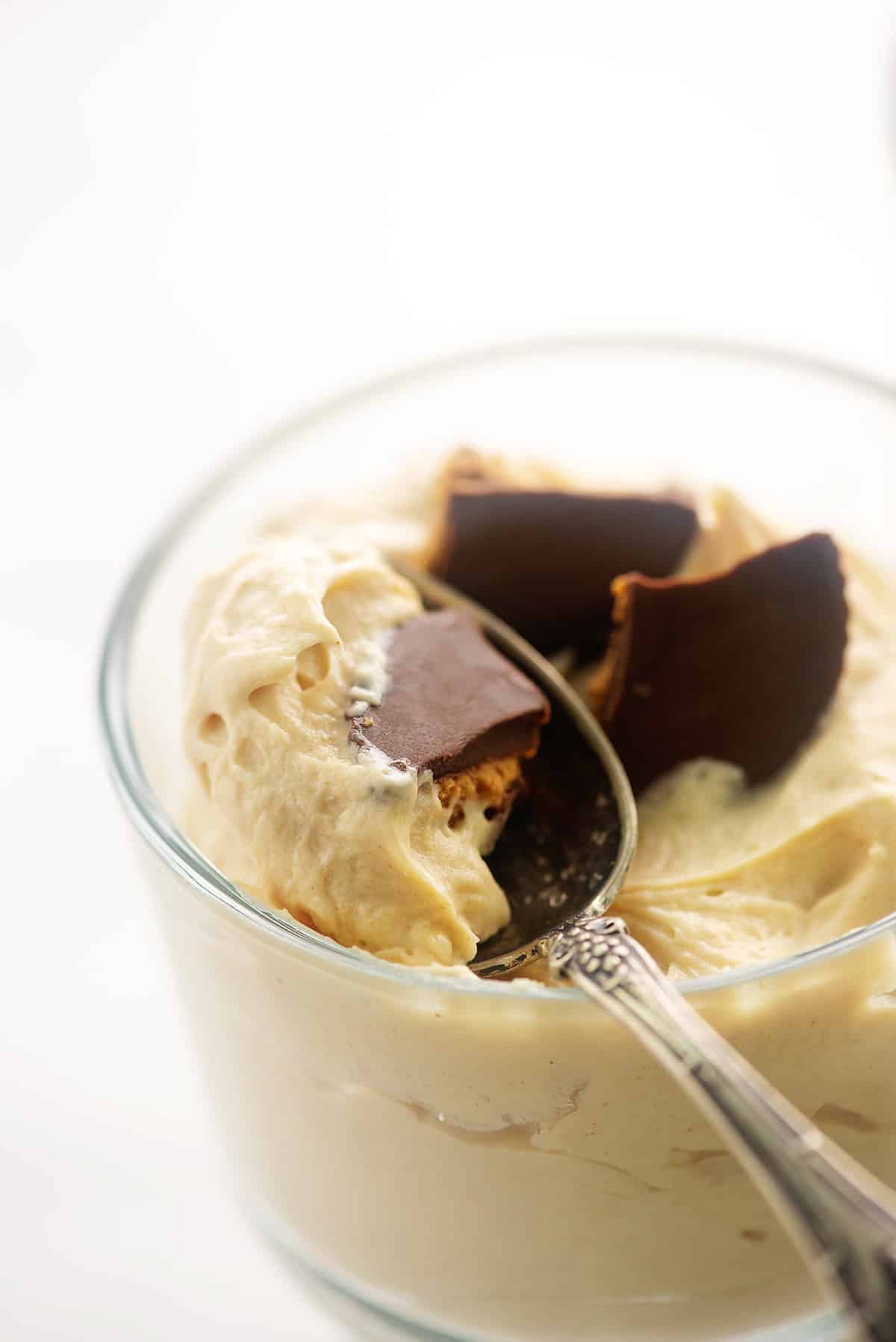 creamy peanut butter mousse in glass dish with spoon.