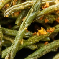 green beans coated in Parmesan on black plate.