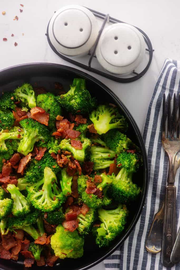 sauteed broccoli and bacon in black dish.