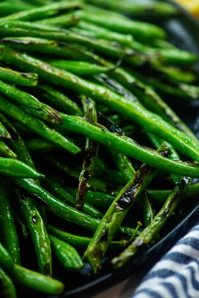 blistered green beans on black plate.