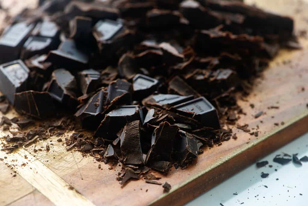 bakers chocolate chopped on wooden cutting board.