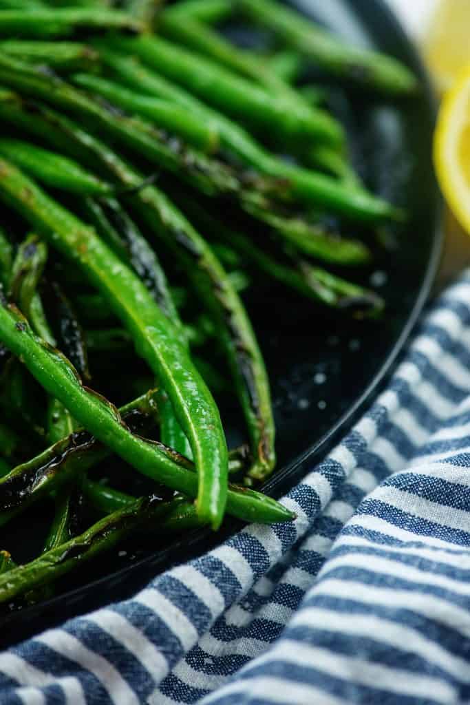 green bean recipe on black plate with striped napkin.