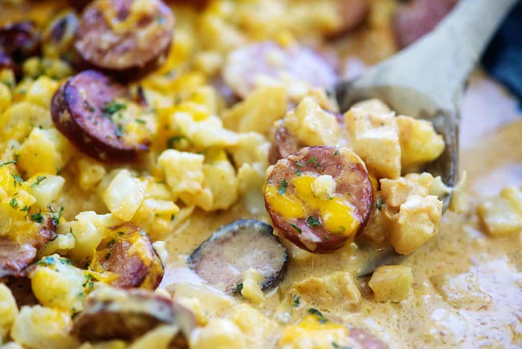 cheesy baked cauliflower with smoked sausage in cast iron skillet.