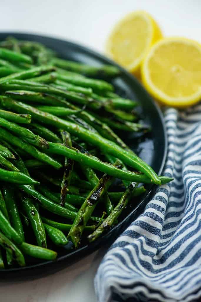 pile of green beans on black plate.