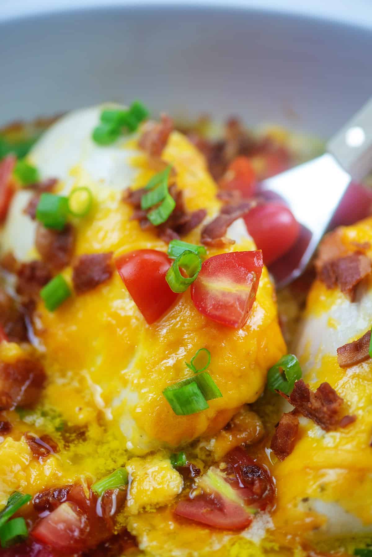 piece of chicken topped with cheese in baking dish.