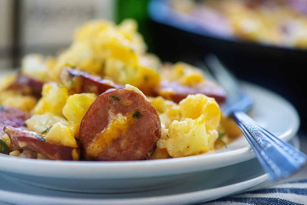 smoked sausage and cheesy cauliflower on white plate.