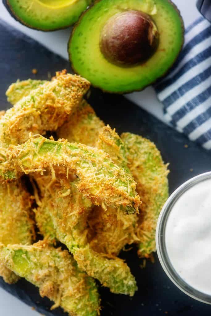 overhead view of avocado fries piled on black board.