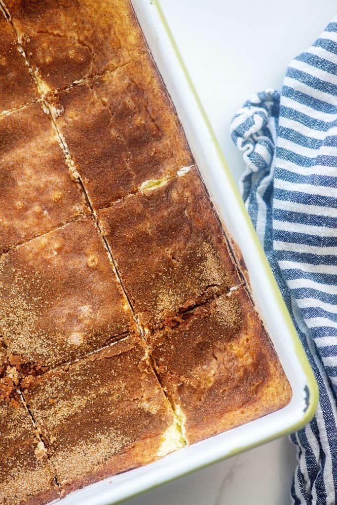 sliced snickerdoodle cheesecake bars in white baking dish.