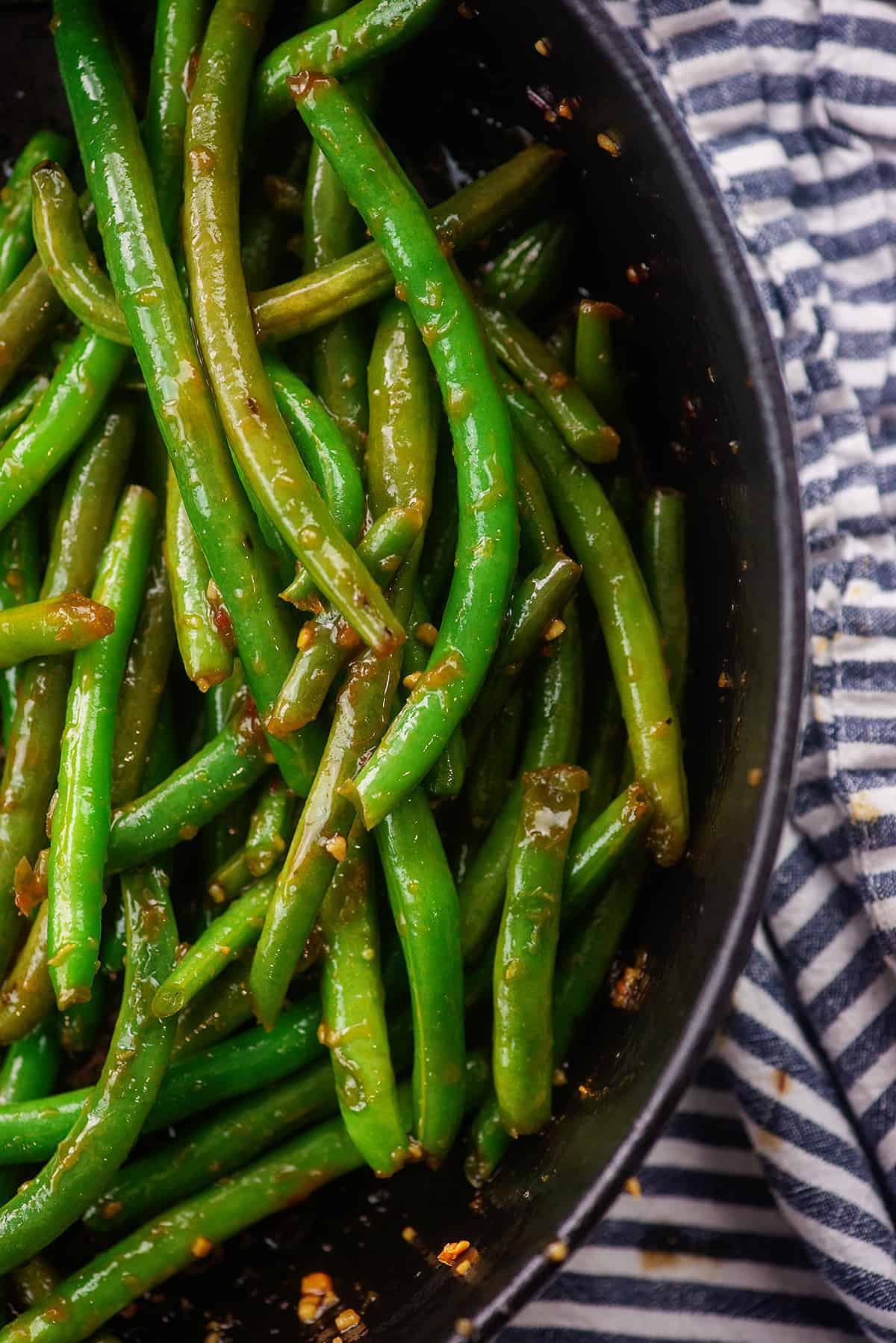 Overhead view of Szechuan green beans in black bowl.