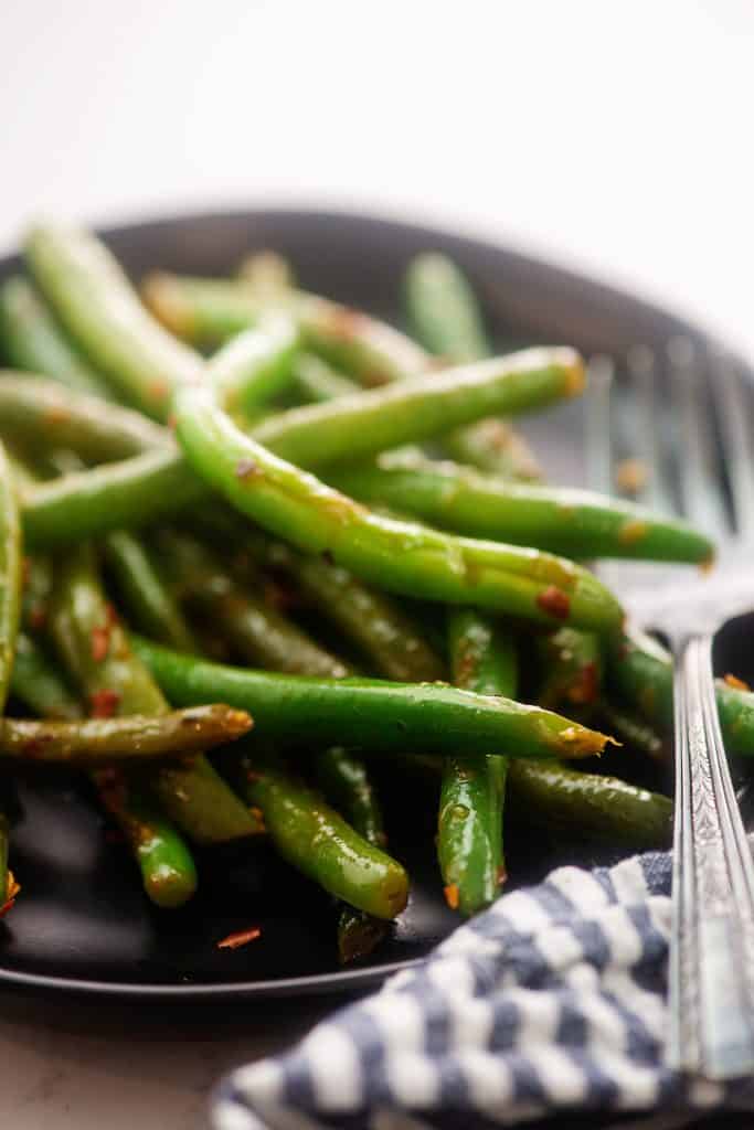 green beans on black plate with fork.