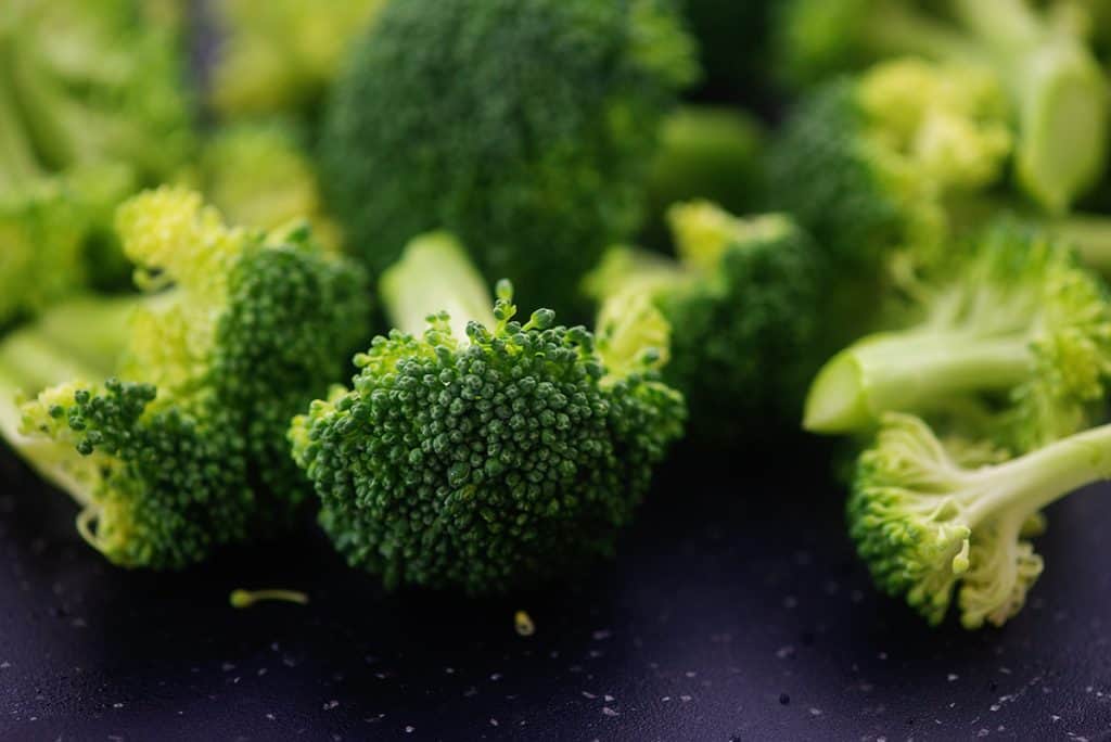 chopped broccoli florets on cutting board.