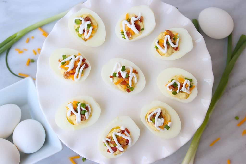 overhead view of keto deviled eggs topped with cheddar, bacon, and sour cream.