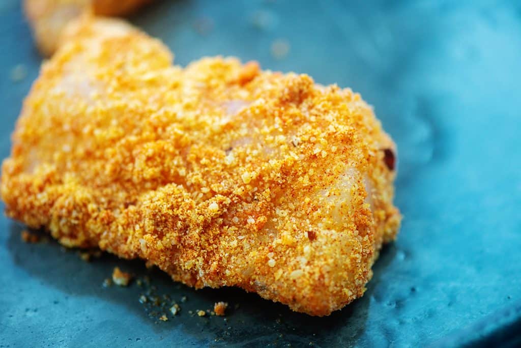 cod coated in Parmesan and almond flour on baking sheet.