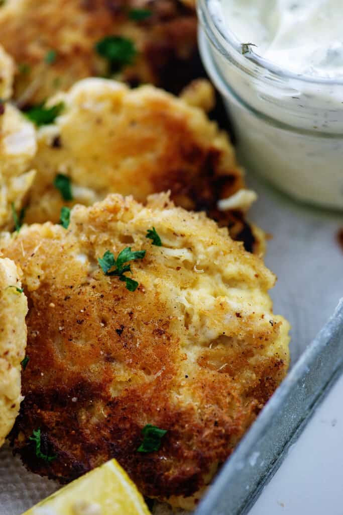 crab cakes and tartar sauce in metal tray.