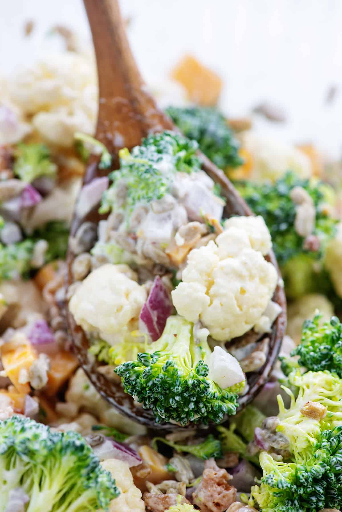 broccoli and cauliflower salad on wooden spoon.