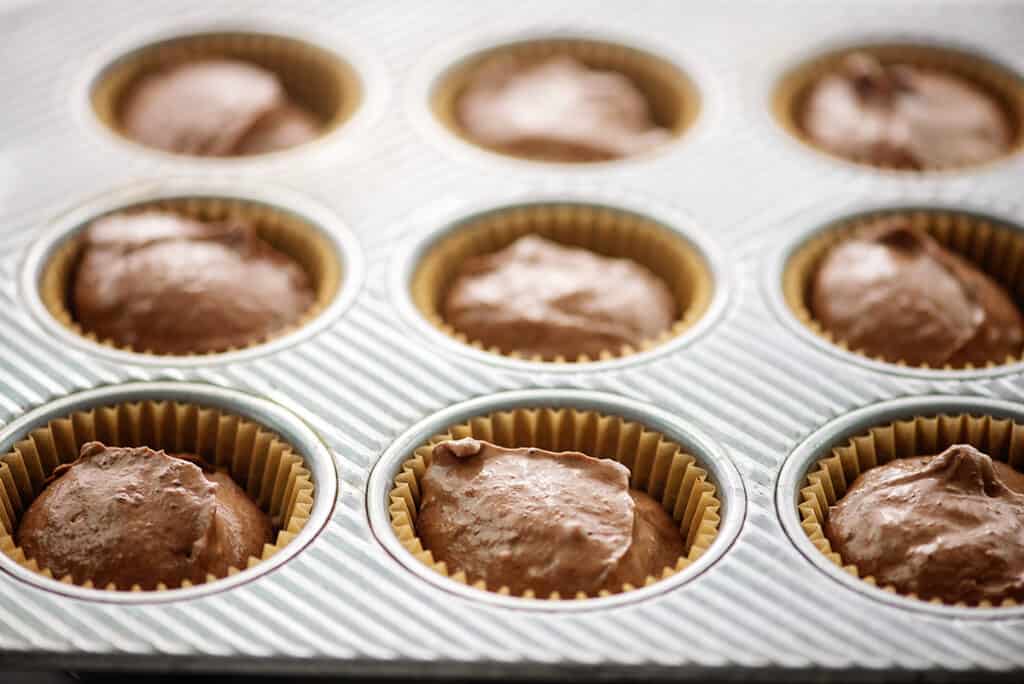 muffin tin filled with keto chocolate cheesecake batter.