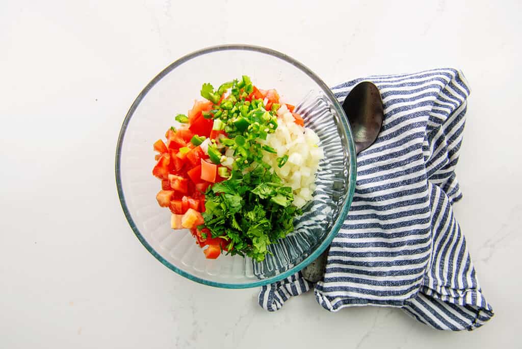 ingredients for pico de gallo in glass bowl.