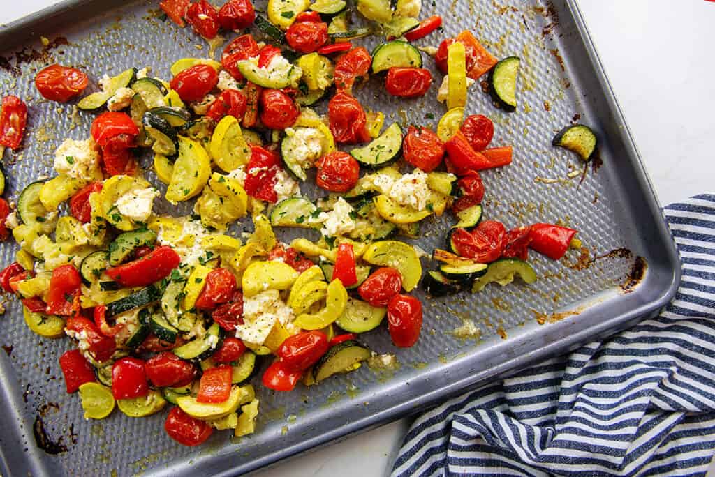 vegetables mixed with feta cheese on baking sheet.