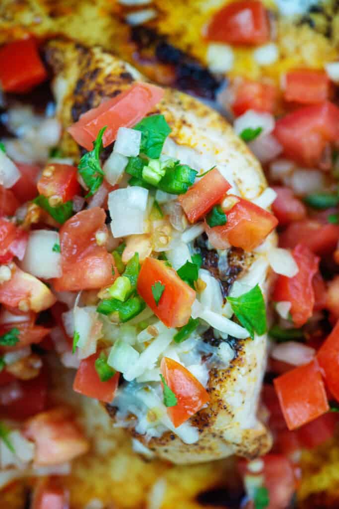 Chicken breast topped with salsa fresca in baking dish.