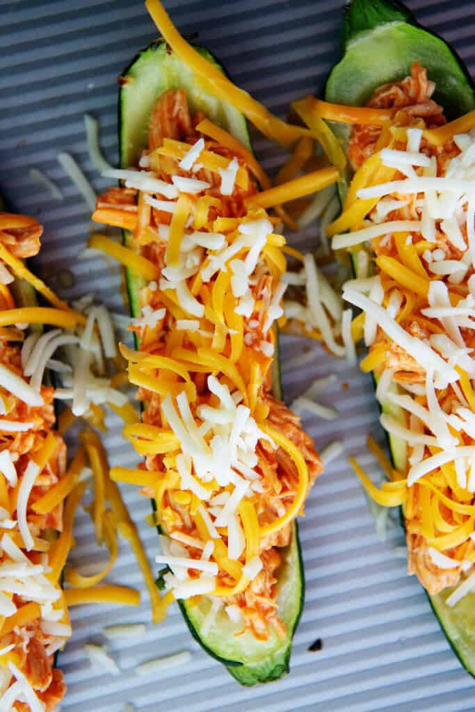 zucchini topped with cheese on baking sheet. 