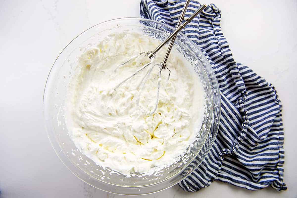 whipped cream in glass mixing bowl with beaters.