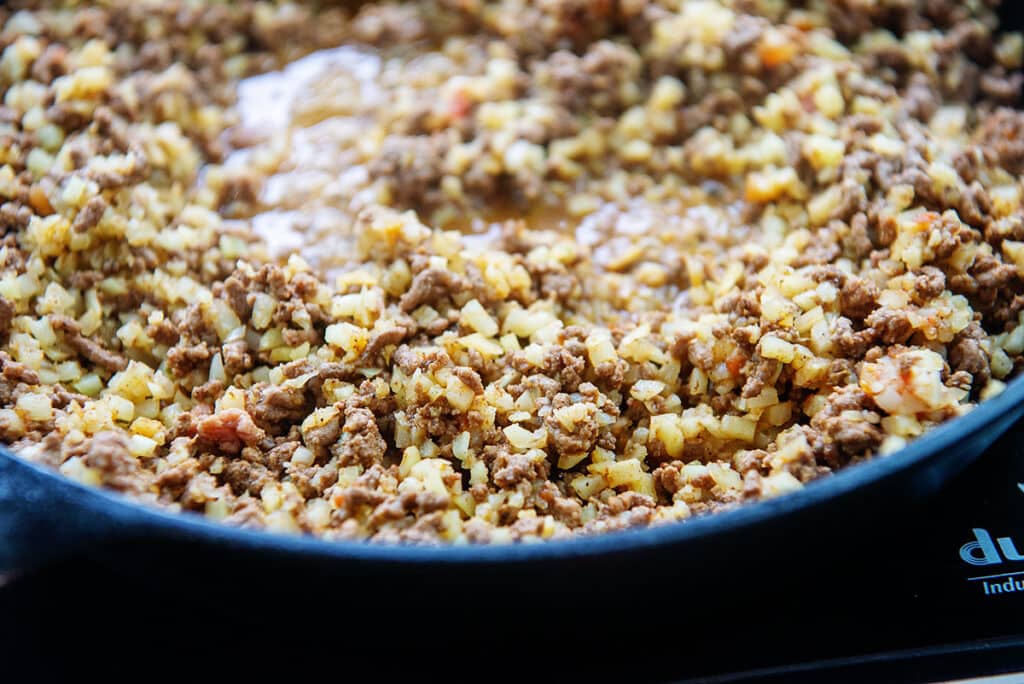 beef and cauliflower rice in cast iron skillet.