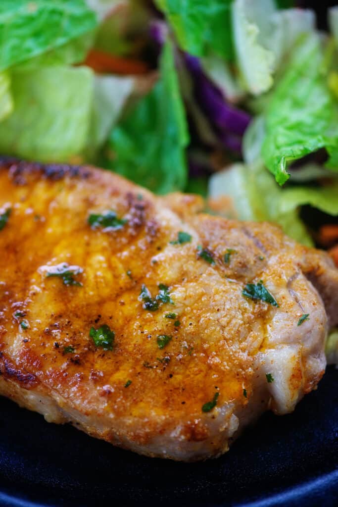 lemon garlic pork chop on plate with salad.