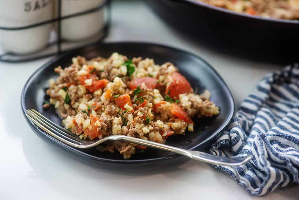 Keto cauliflower rice recipe on black plate.