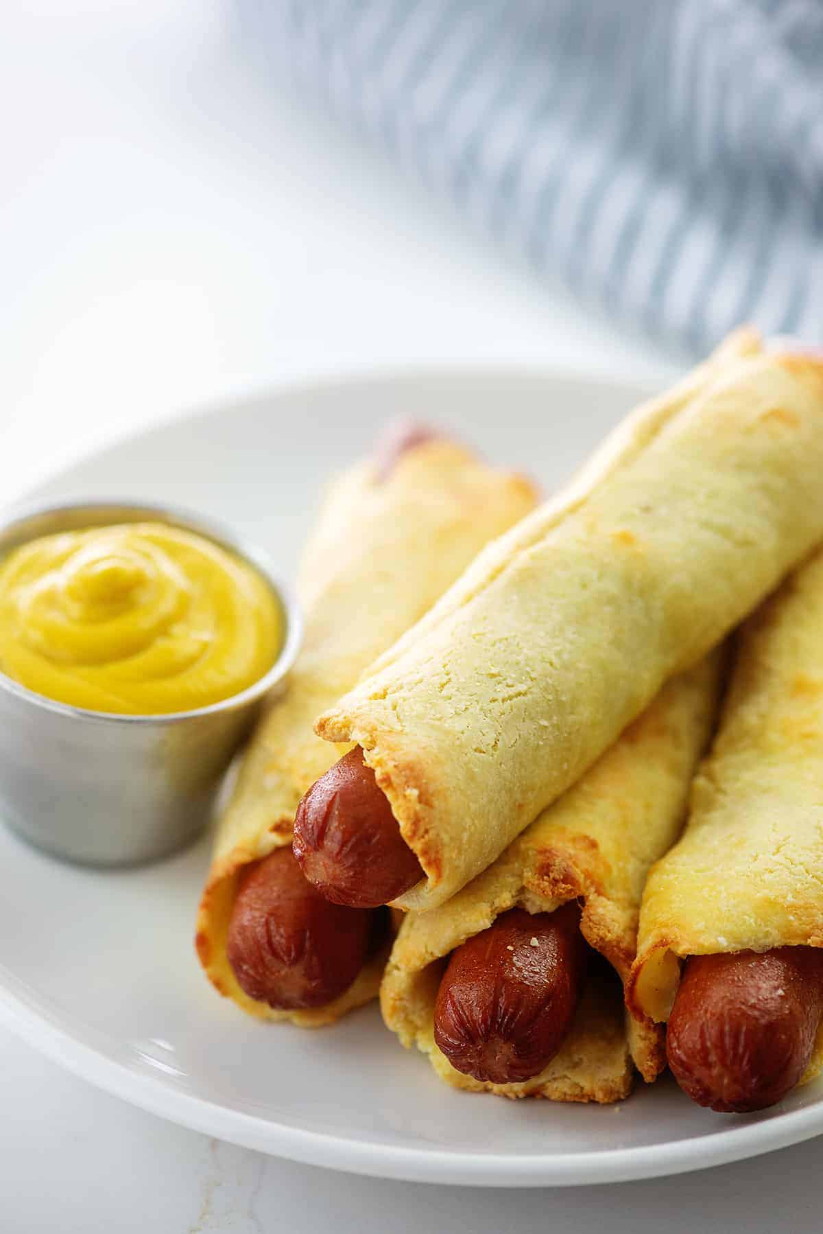 keto pigs in a blanket piled next to mustard.