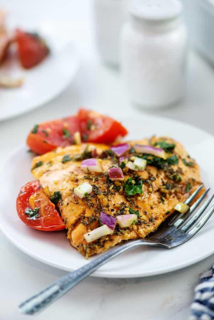 baked salmon bruschetta on white plate with vintage fork.