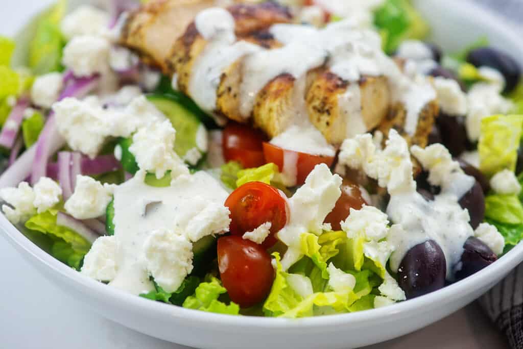 greek chicken salad in white bowl.