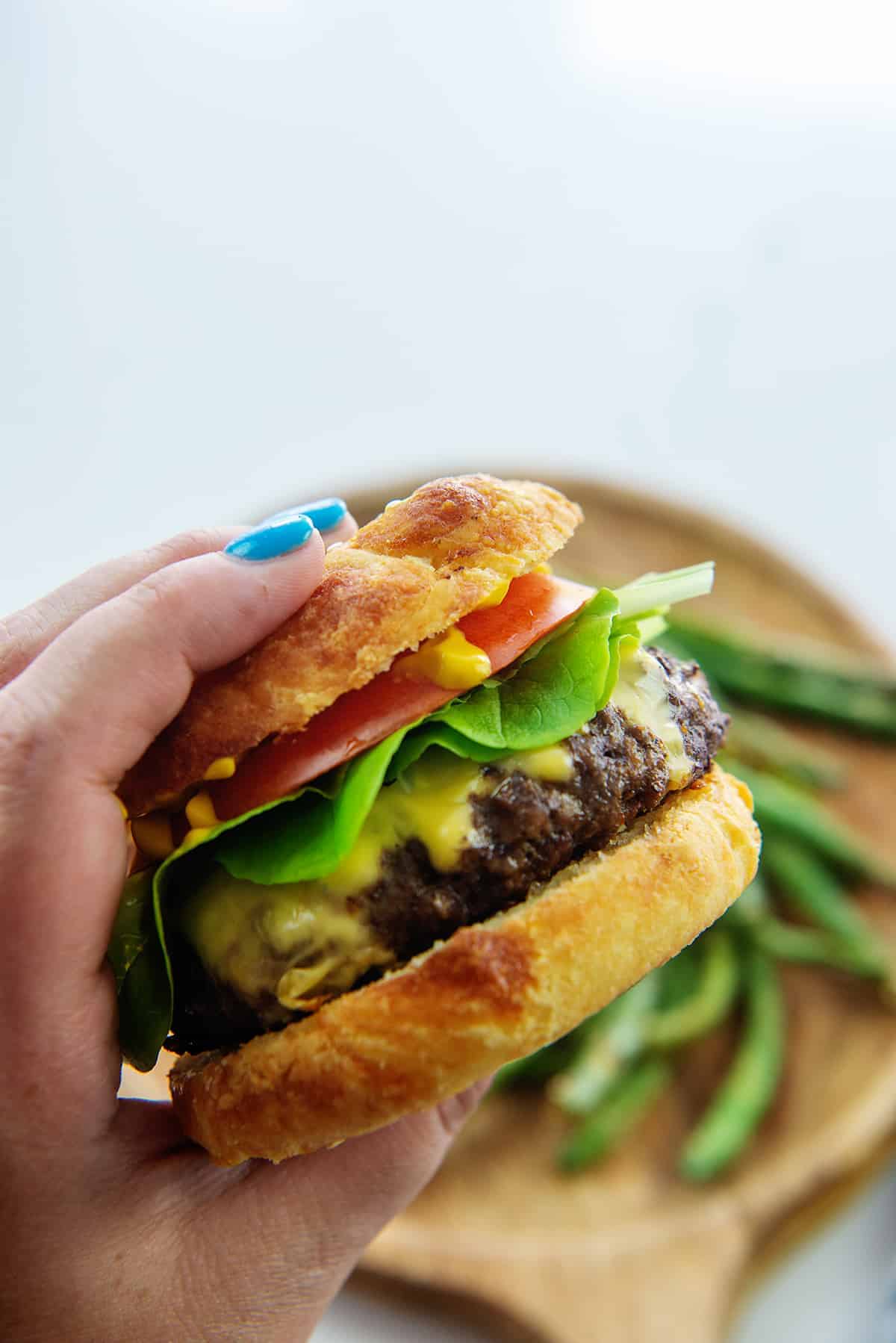 hand holding a cheeseburger on a low carb bun.