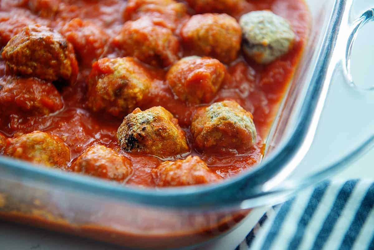 meatballs in marinara sauce in glass dish.