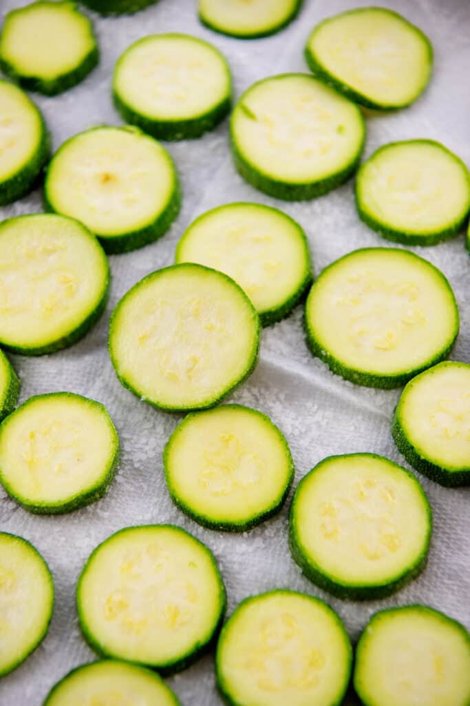 salted zucchini laying on paper towels to release their juices.