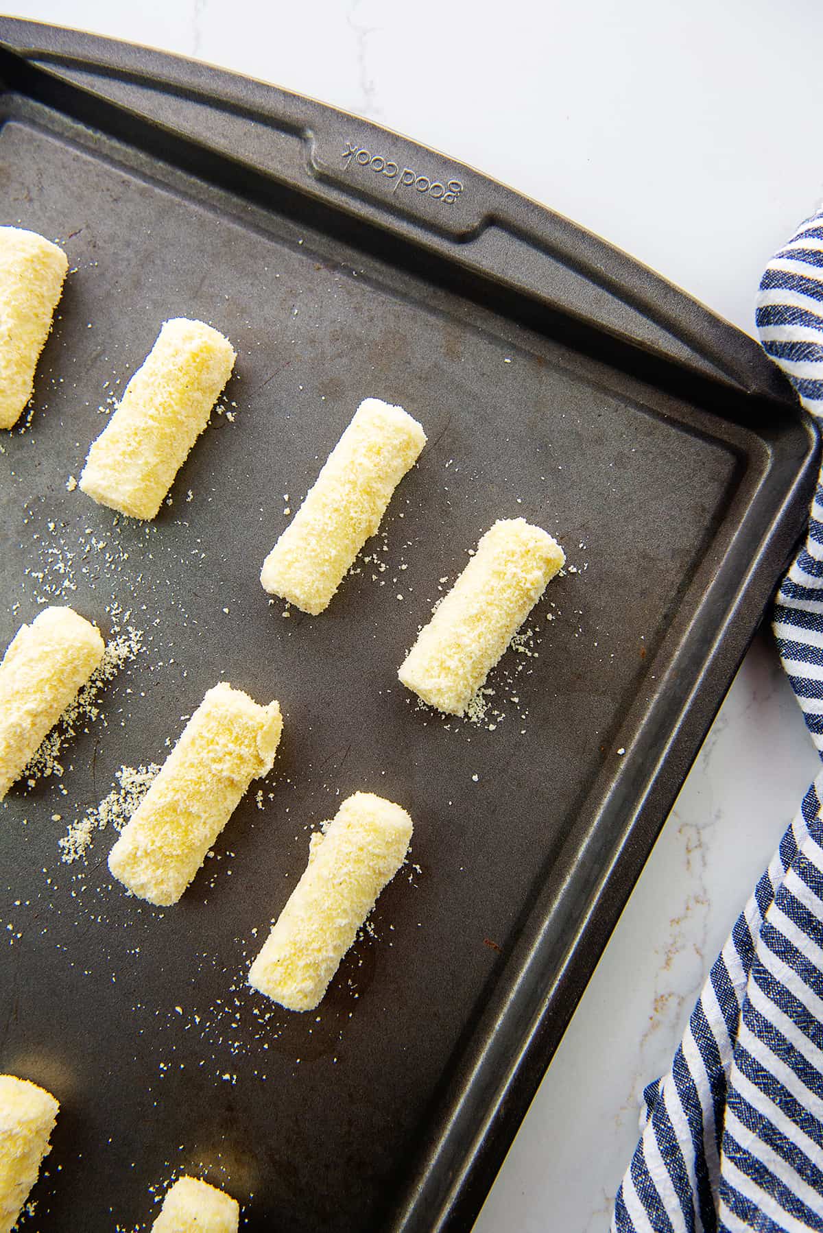 breaded cheese sticks on baking sheet.