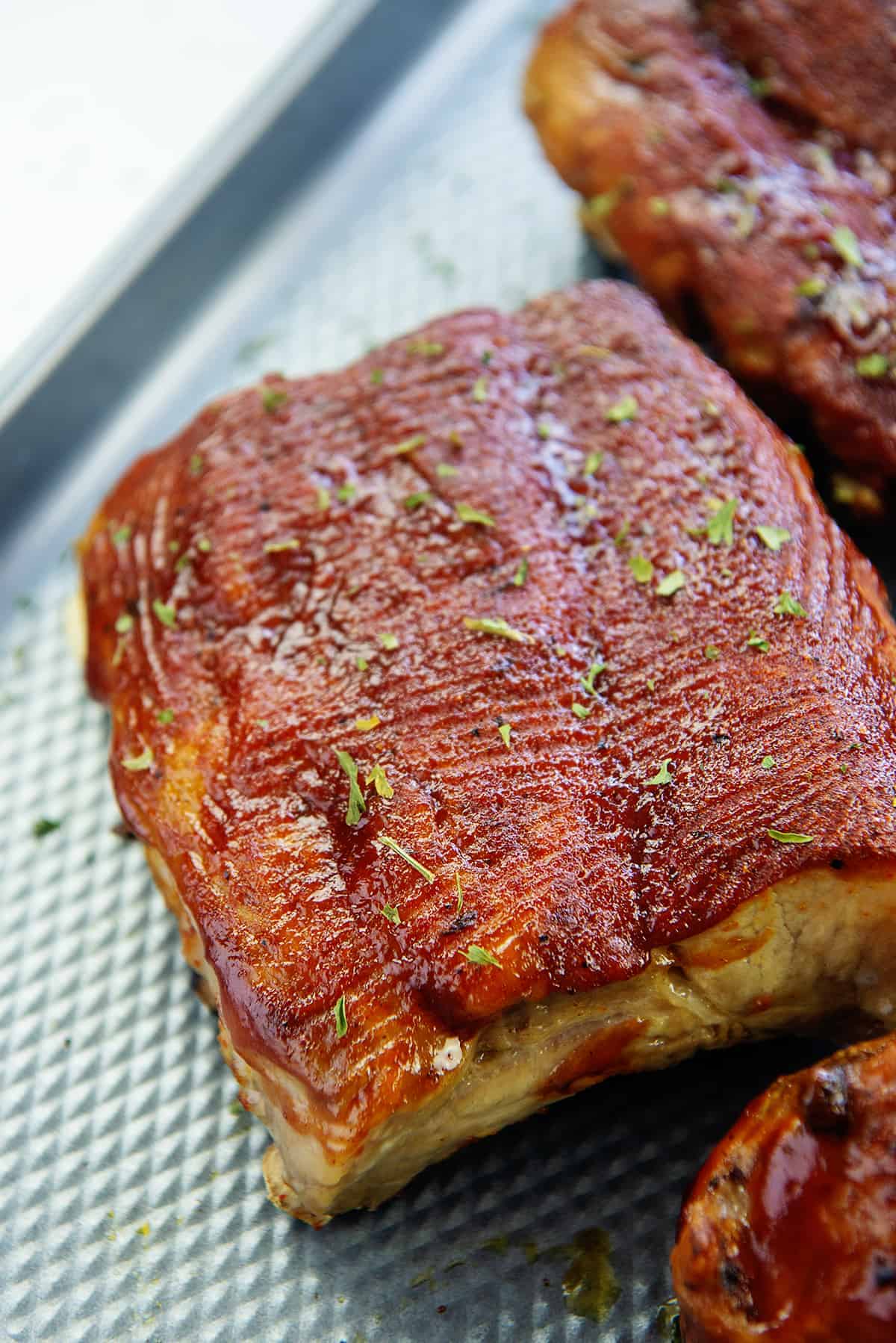 ribs brushed with barbecue sauce on sheet pan.