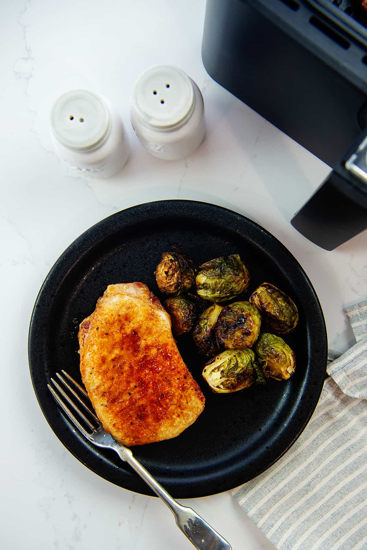 pork chop on plate with Brussels sprouts.