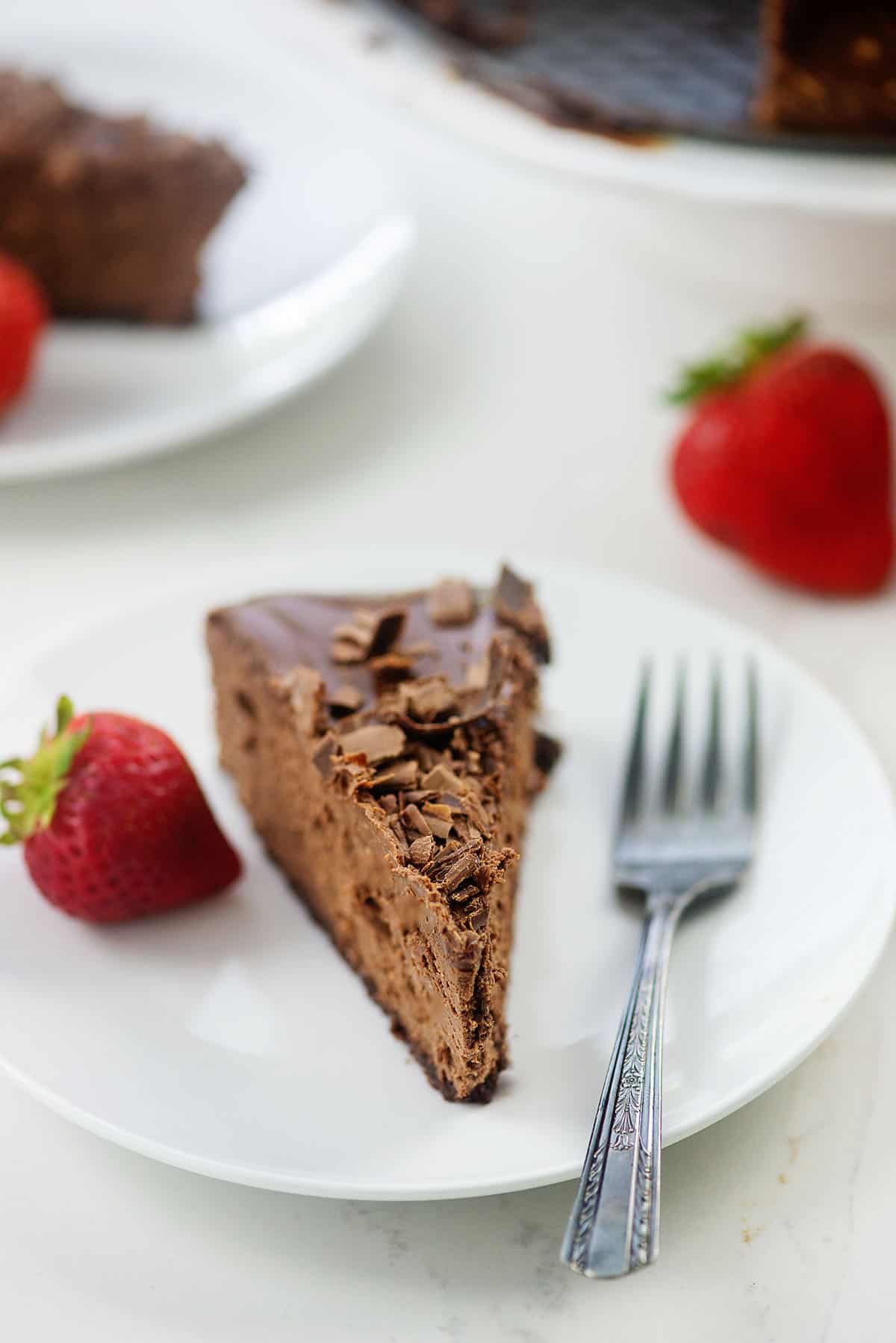 death by chocolate cheesecake on white plate with strawberries.
