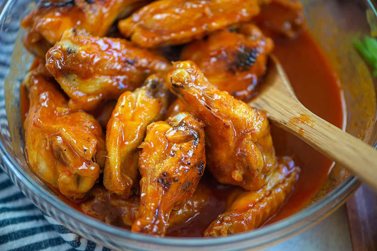chicken wings being tossed in sauce.