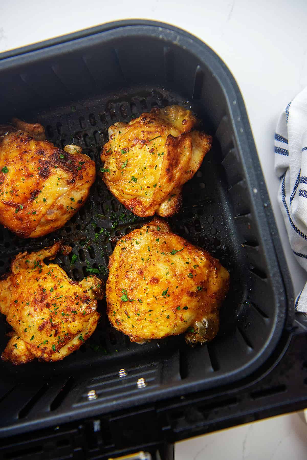 chicken thighs in air fryer basket.