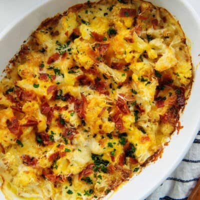 baked cauliflower with bacon in white dish.