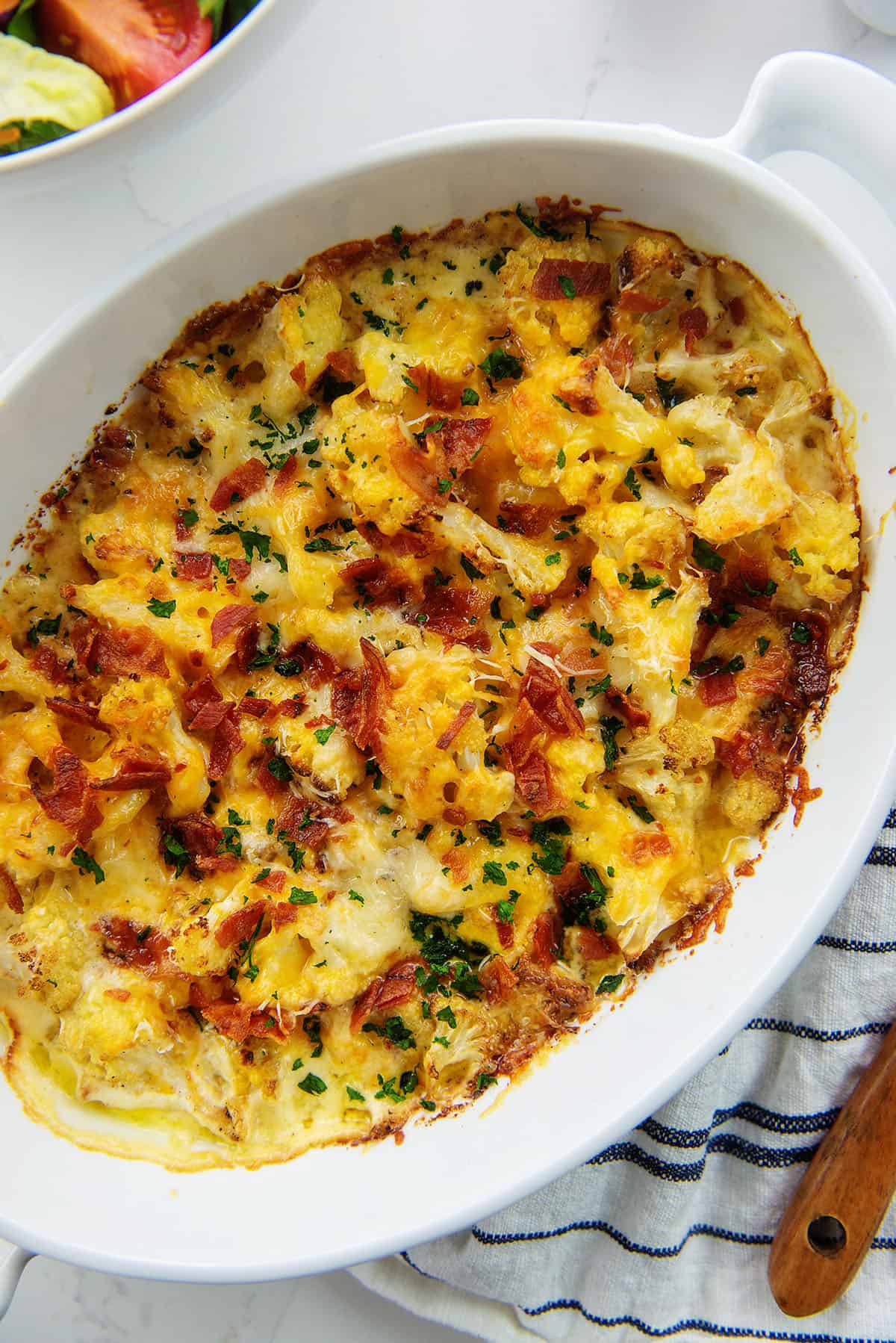 baked cauliflower with bacon in white dish.