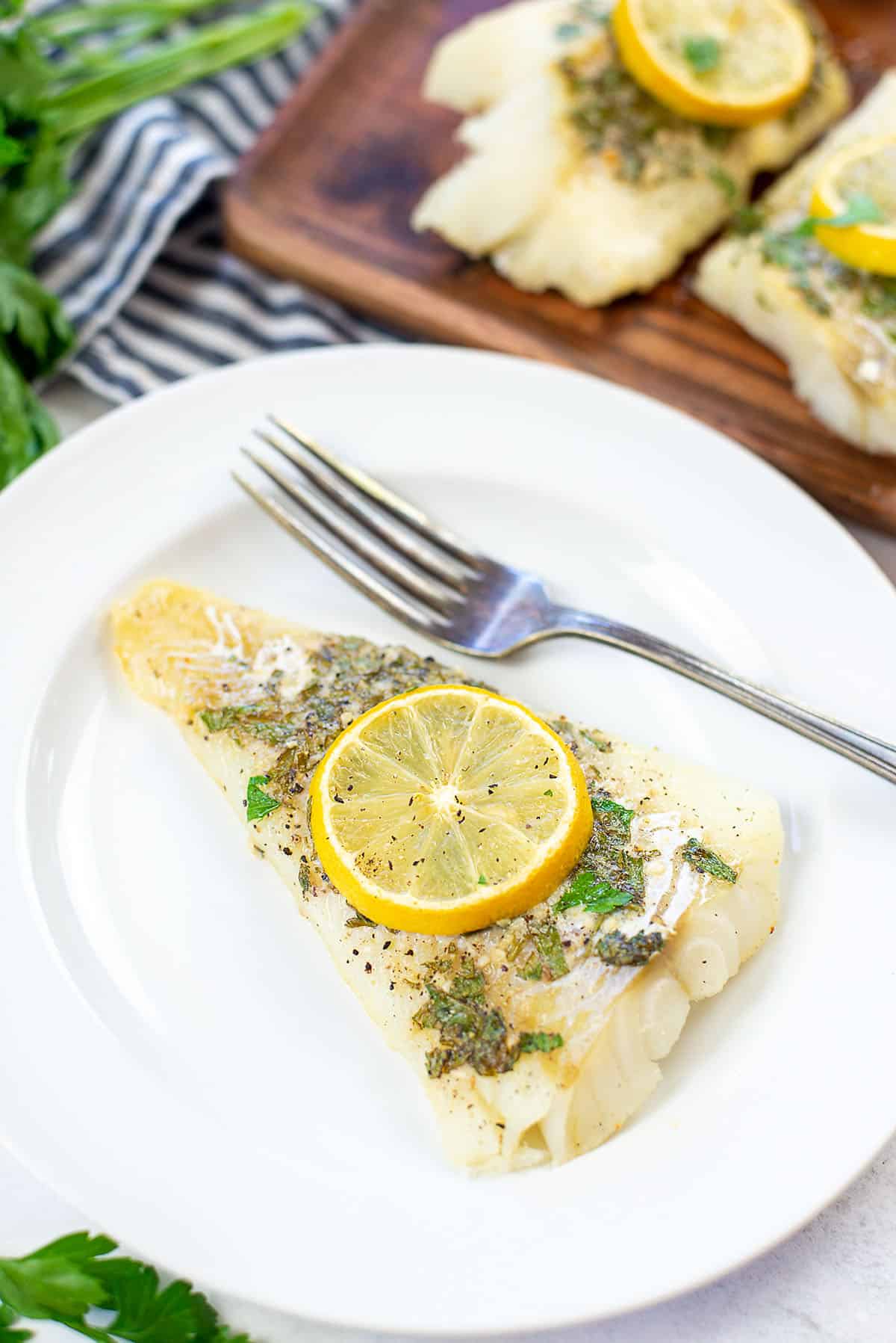 lemon baked cod on white plate.