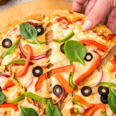 Hand grabbing a slice of keto chicken crust pizza.